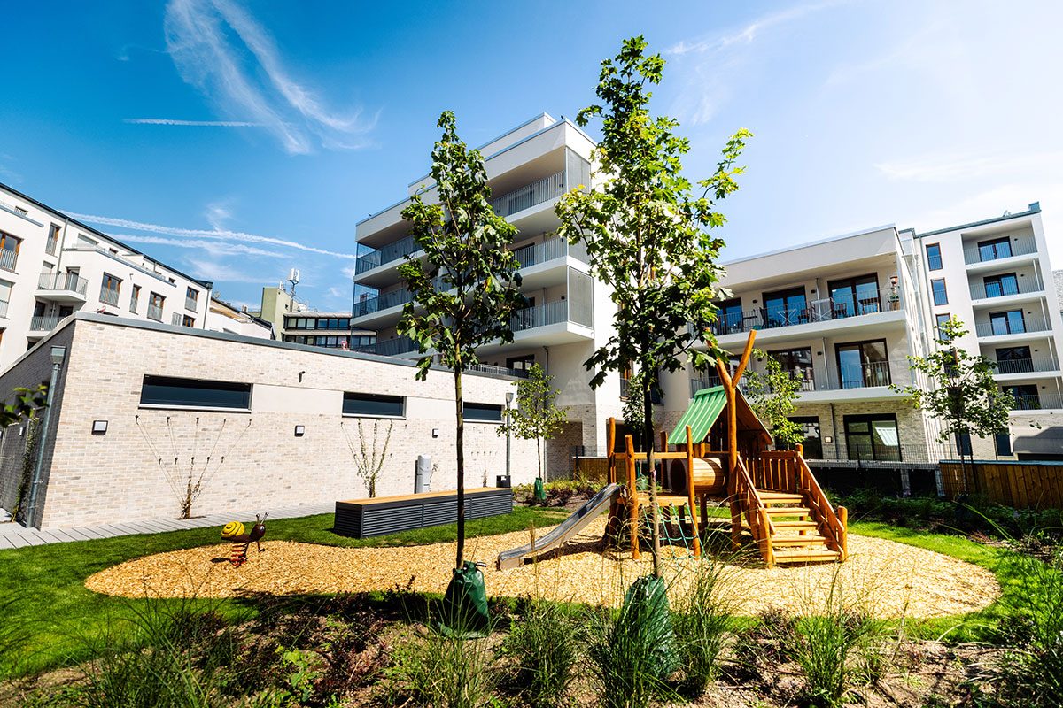 Begrünter Innenhof des Berger Quartiers mit Spielplatz und Neubauten mit Balkonen